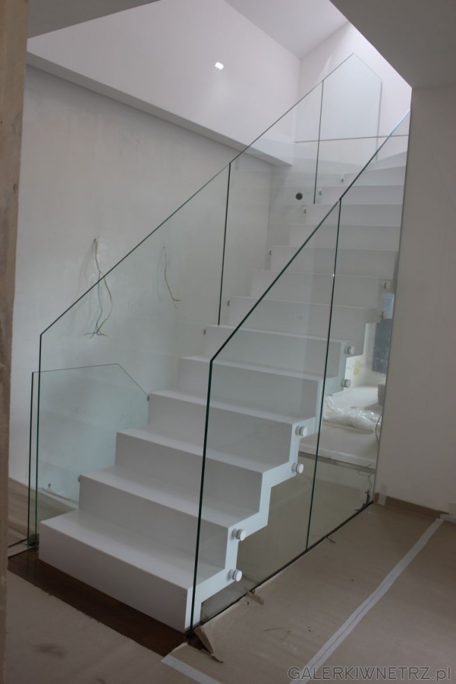 Białe schody z dwóch stron ograniczone szklanymi balustradami o ostrym zakończeniu. ...