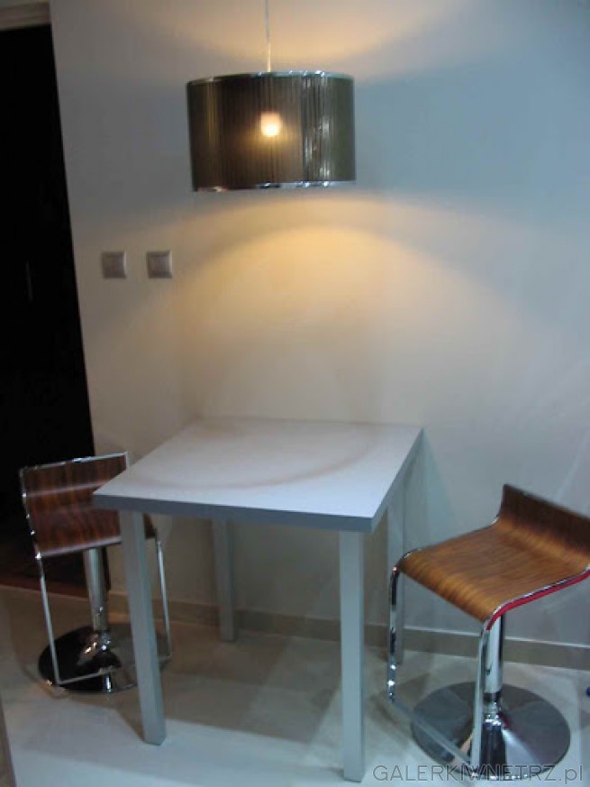 Mały stolik z dwoma krzesłami-prowizoryczna jadalnia.Na podłodze Szkliwione Płytki ...